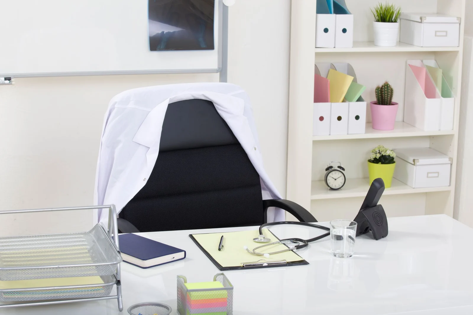 Escritorio de consulta con estetoscopio, silla y carpetas. Fotografía de stock ilustrativa.